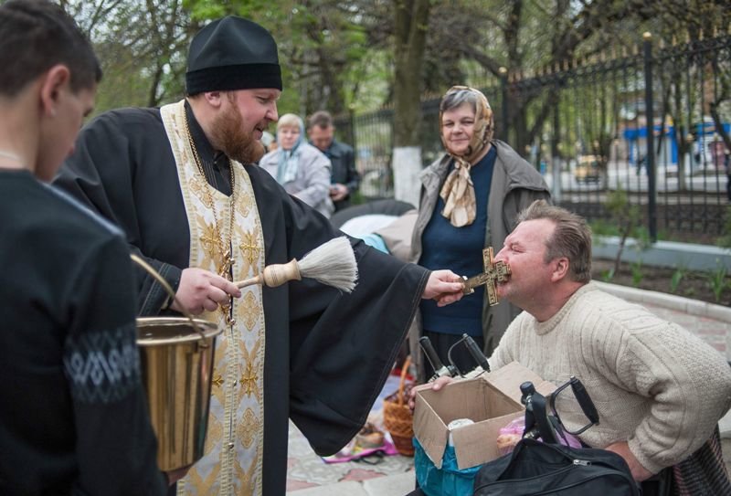 Un sacerdote ortodoxo da a besar un crucifijo a un ciudadano de Slaviansk.