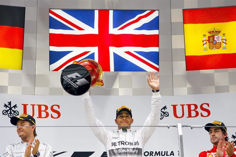 El británico Lewis Hamilton saluda desde el podio del Gran Premio de China, flanqueado por Nico Rosberg y Fernando Alonso.