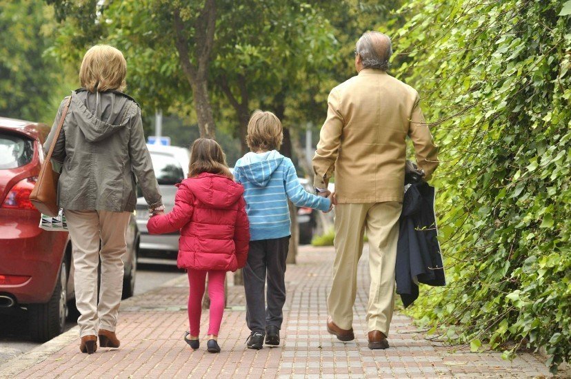 Una pareja de abuelos camina por la calle con sus nietos.