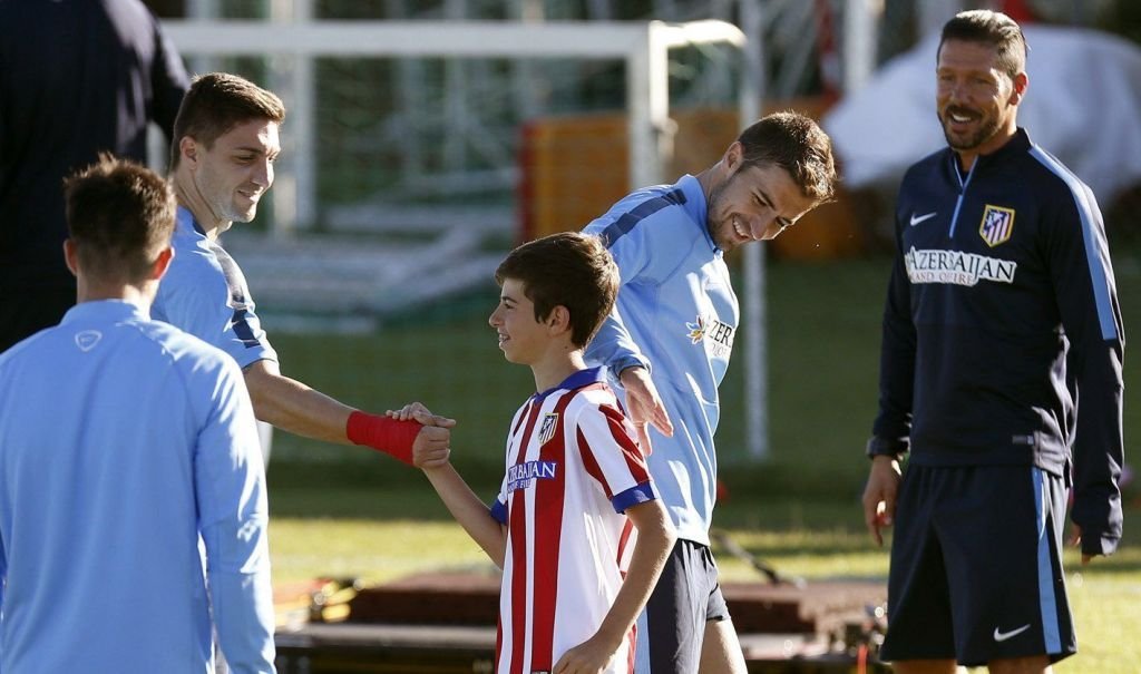 El capitán del Atlético, Gabi (d.), saluda a un joven aficionado antes de un entrenamiento.