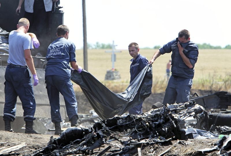 Un grupo de operarios ucranianos introducen un cadáver en un camión.