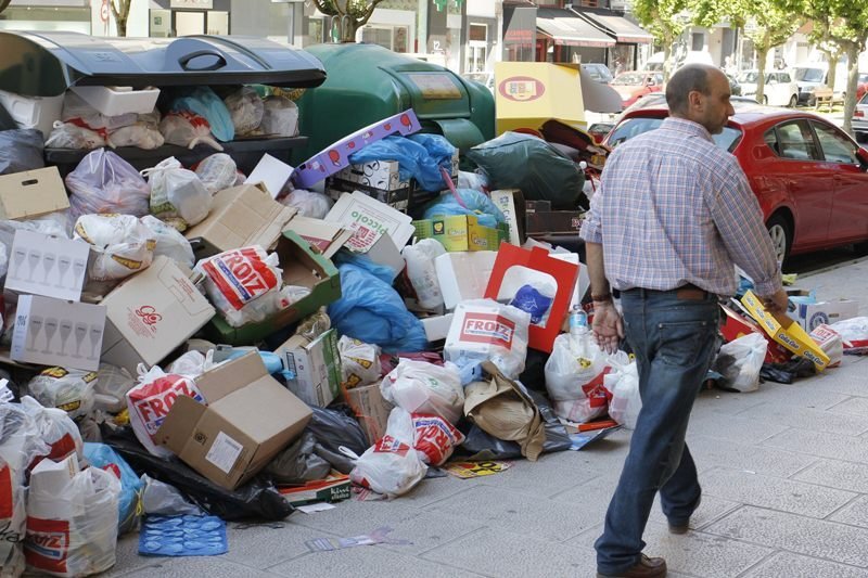 Un hombre pasa ante una zona de contenedores rebosantes de bolsas de basura.