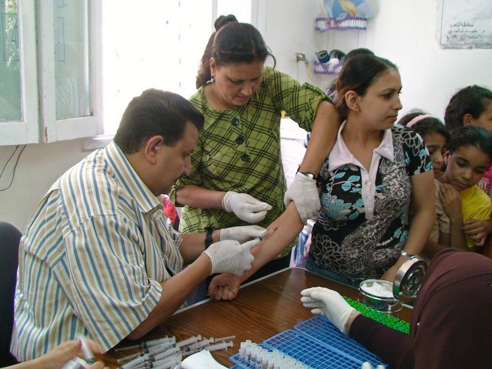Un grupo de médicos vacuna a una mujer contra la hepatítis vírica.