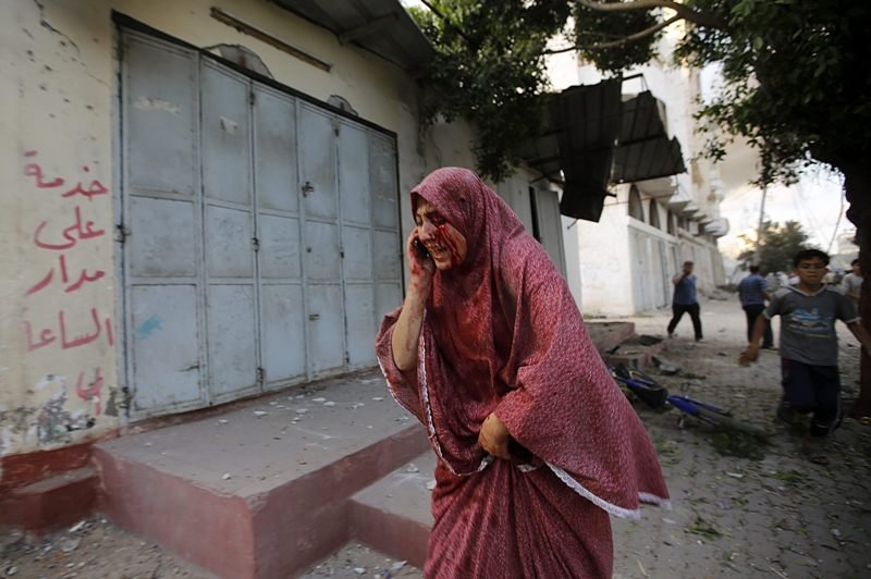 Una mujer herida huye de la escuela bombardeada en Gaza.