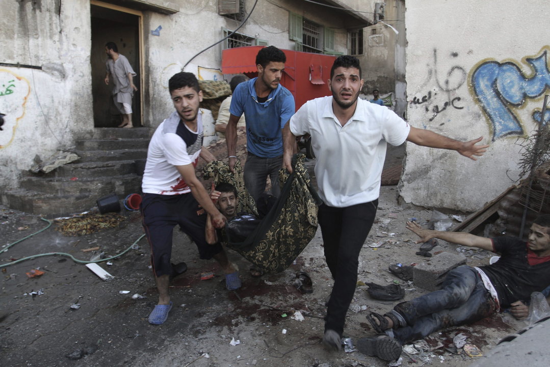 Tres jóvenes trasladan a un herido durante los bombardeos de ayer en Gaza.