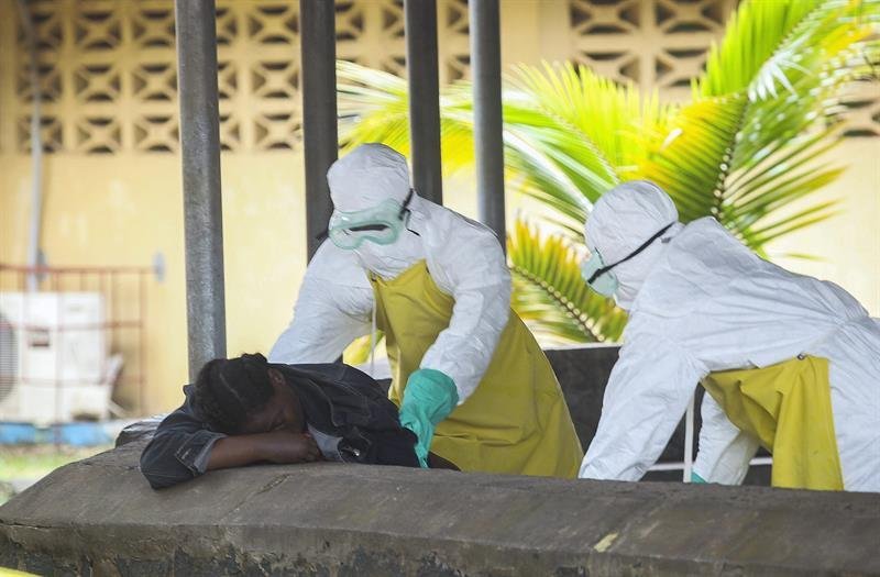 Enfermeras liberianas recoger un cadáver debe al Ébola de la sala de espera del hospital ELWA en Monrovia, Liberia