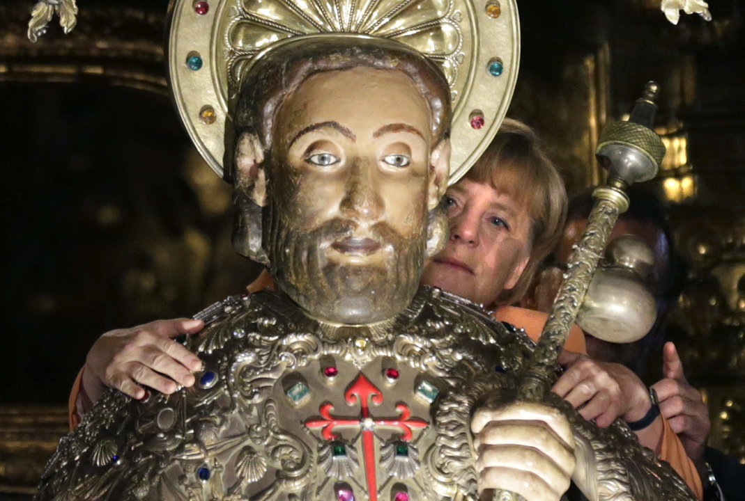 Merkel observa el abrazo de Rajoy a la imagen del Apóstol Santiago.