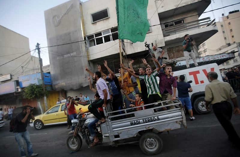 Ciudadanos palestinos ondean una bandera de Hamás durante la celebración del alto el fuego.