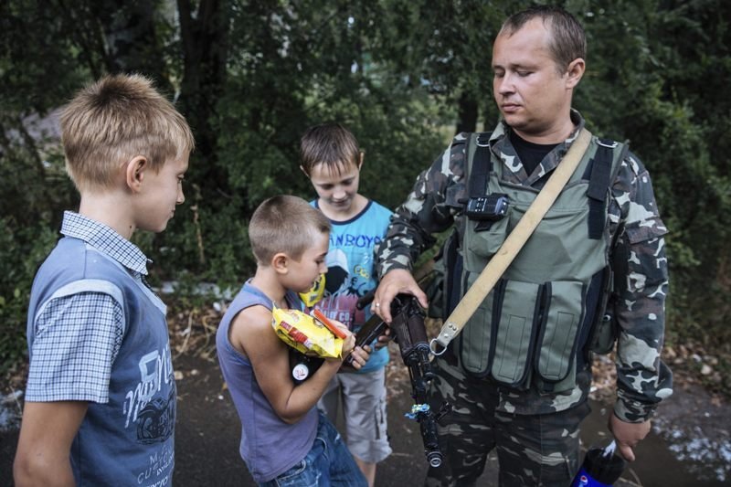 Un soldado ucraniano enseña su arma a unos niños en Dzerzhynsk.