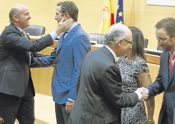 Los ministros de Economía, Luis de Guindos, y de Hacienda, Cristóbal Montoro, saludan a los nuevos cargos que tomaron posesión esta semana