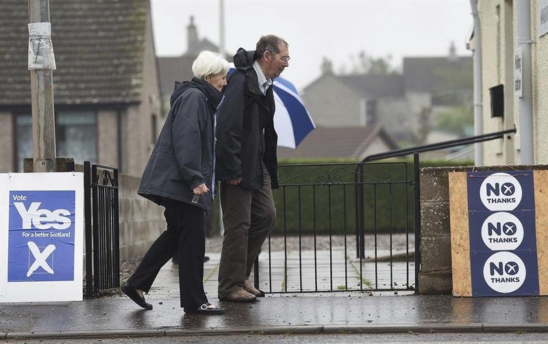 Una pareja pasa delante de una pancarta a favor del "sí" (i) y otra del "no" (d) a la independencia de Escocia del Reino Unido