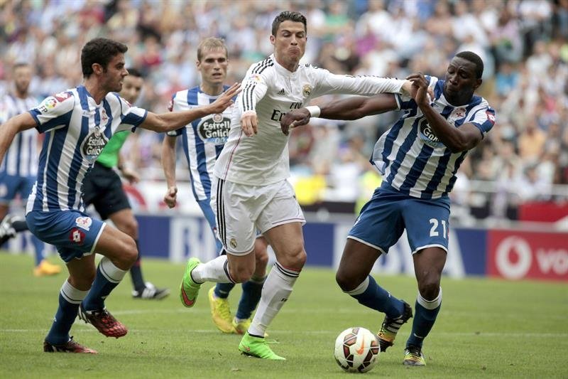 El delantero portugués del Real Madrid Cristiano Ronaldo (c) pelea un balón con los jugadores del Deportivo Juan Domínguez (i) y Modibo Diakité