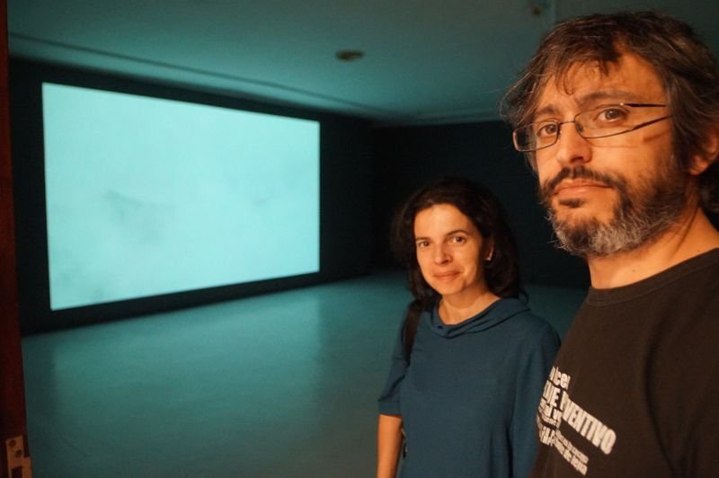 Vanesa Otero, la comisaria, y Juan Adrio, el artista, posan en la sala de la Fundación Laxeiro, con la gran pantalla donde se visualizan las fotografías, el único foco de atracción del espacio.