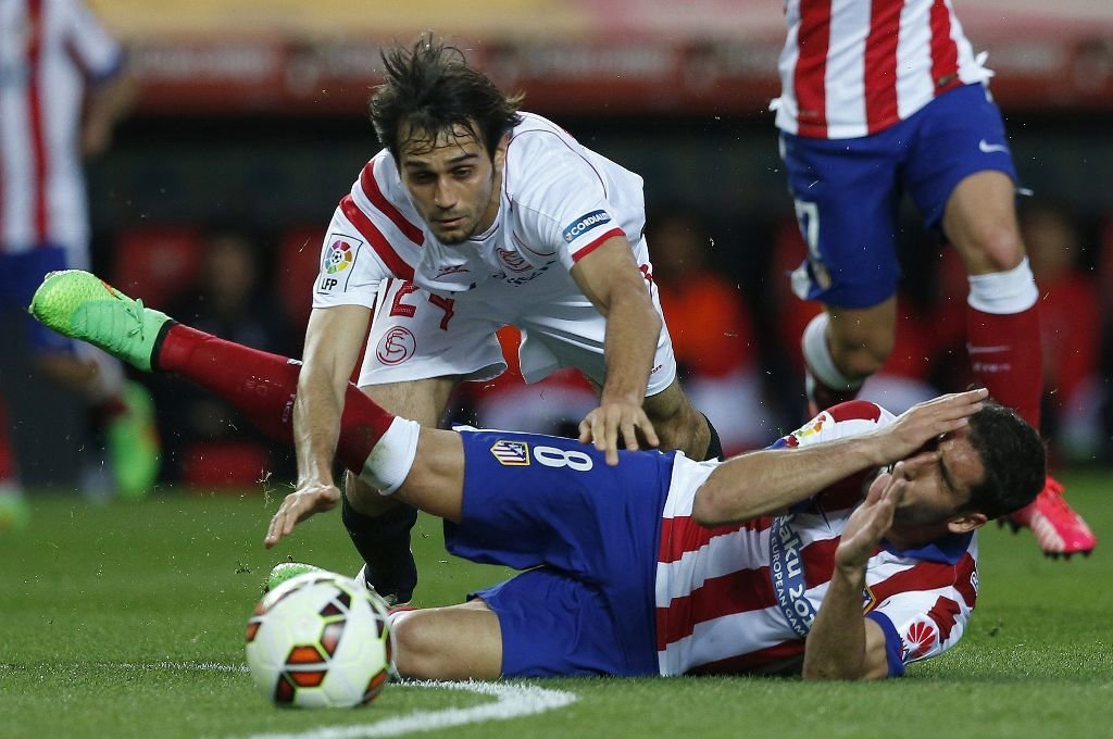 El sevillista Arribas y el atlético Raúl García caen al suelo durante el partido de ayer en el Sánchez Pizjuán.