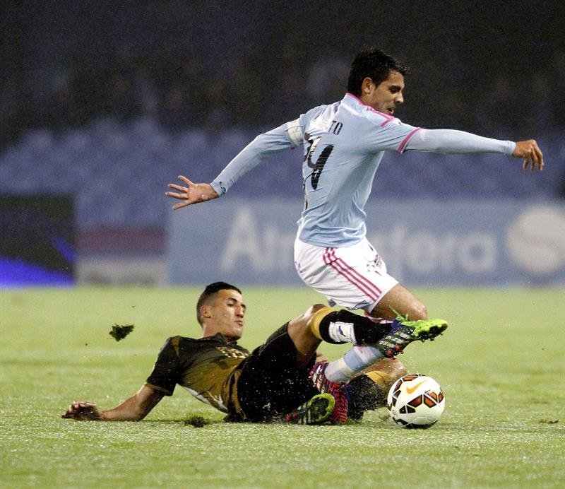 El centrocampista argentino del Celta de Vigo Augusto Fernández (d) cae ante el centrocampista del Elche Adrián González