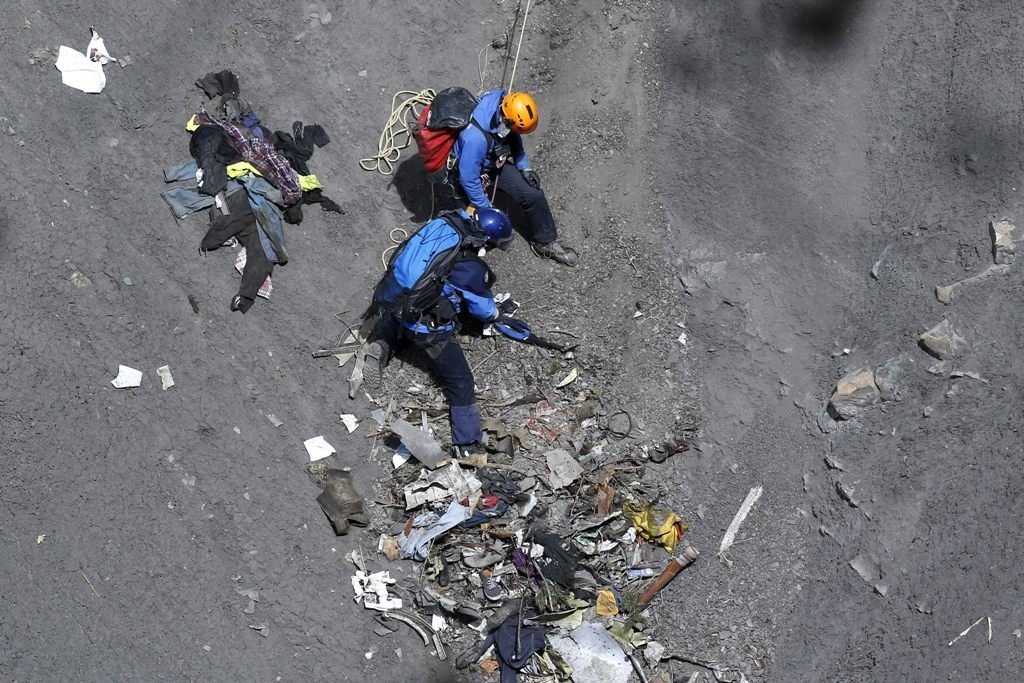 Dos miembros de los equipos de rescate recogen restos del avión siniestrado en los Alpes.