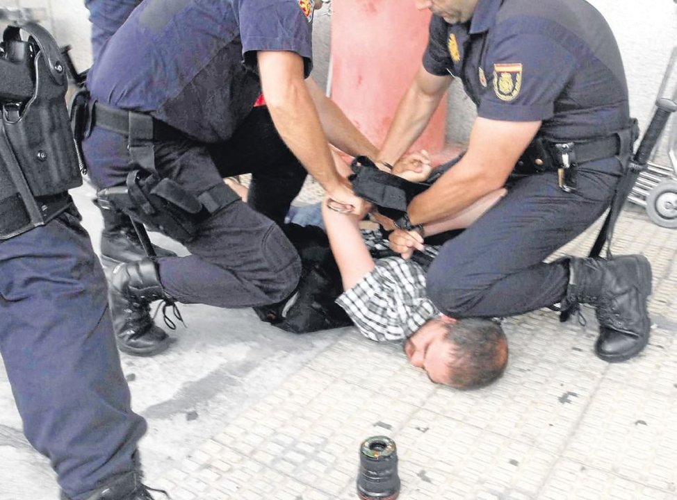 El fotógrafo reducido por la Policía y esposado en el suelo.