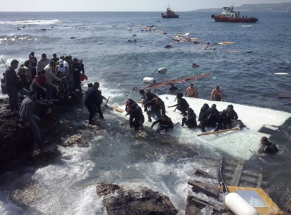 Un grupo de personas ayuda a llegar a tierra a varios inmigrantes ilegales en la isla de Rodas.