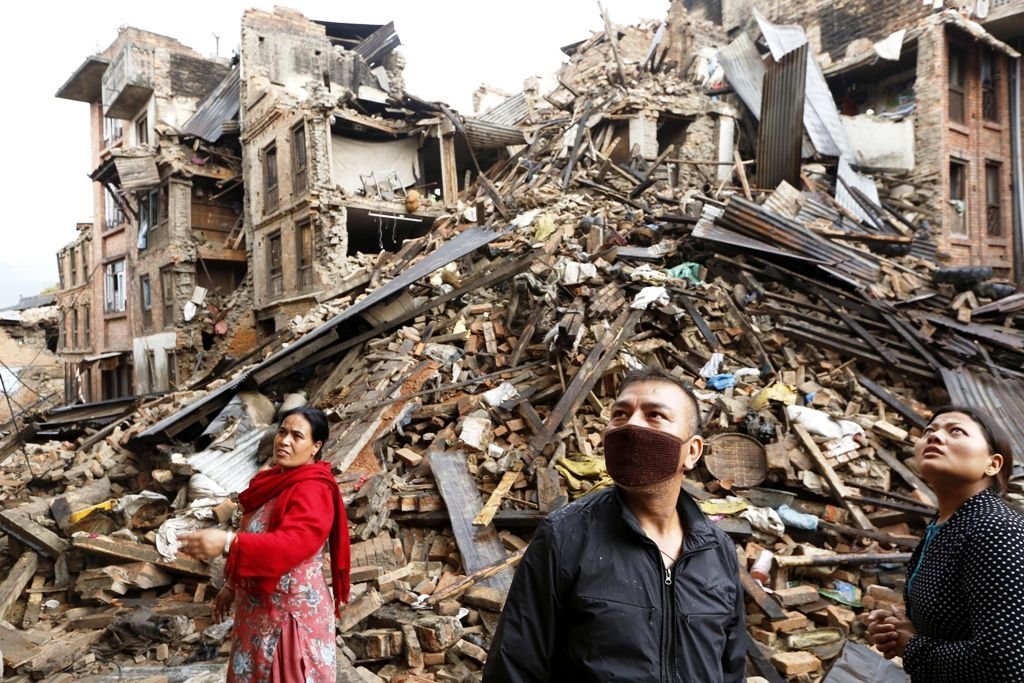 Varias personas observan los restos de varios edificios destrozados en el distrito de Bhaktapur.