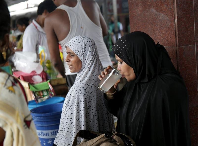 Una mujer bebe un vaso de agua de cal en Calcuta (India)