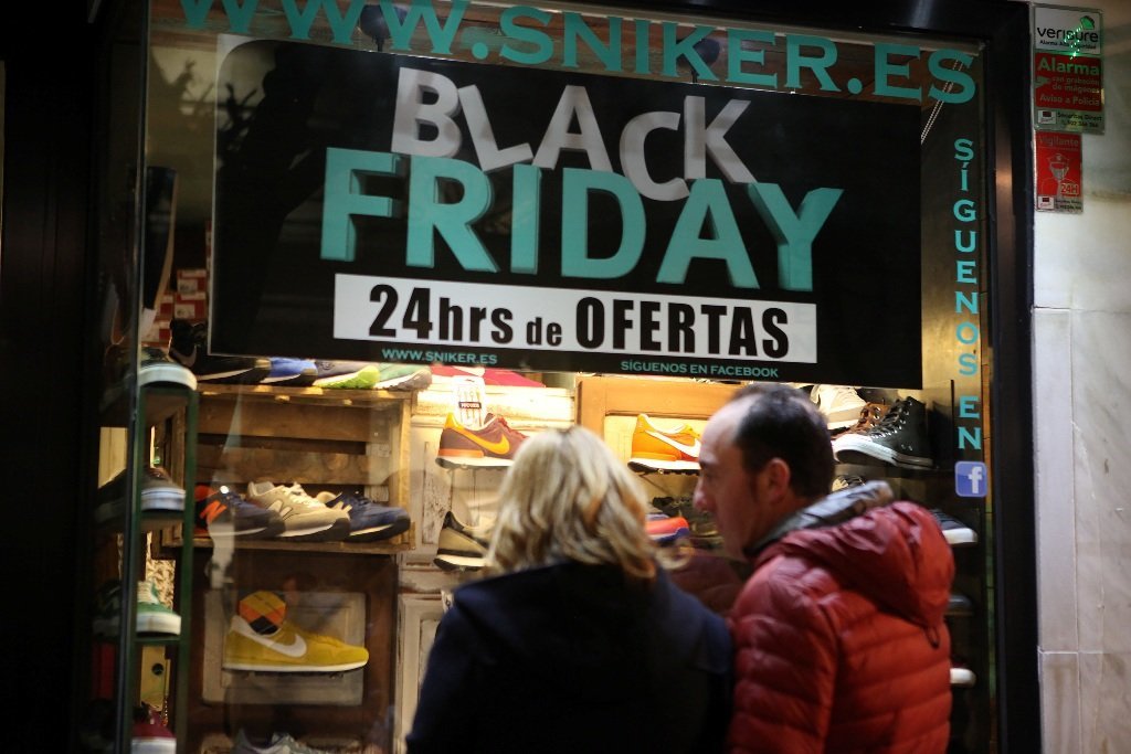 Dos personas contemplan el escaparate de un establecimiento con ofertas del  "Viernes Negro".