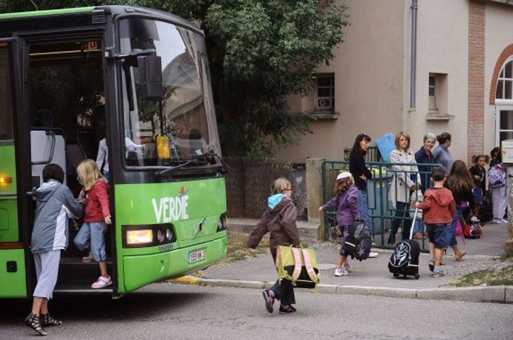 Un grupo de escolares desciende de un autobús para entrar al colegio.