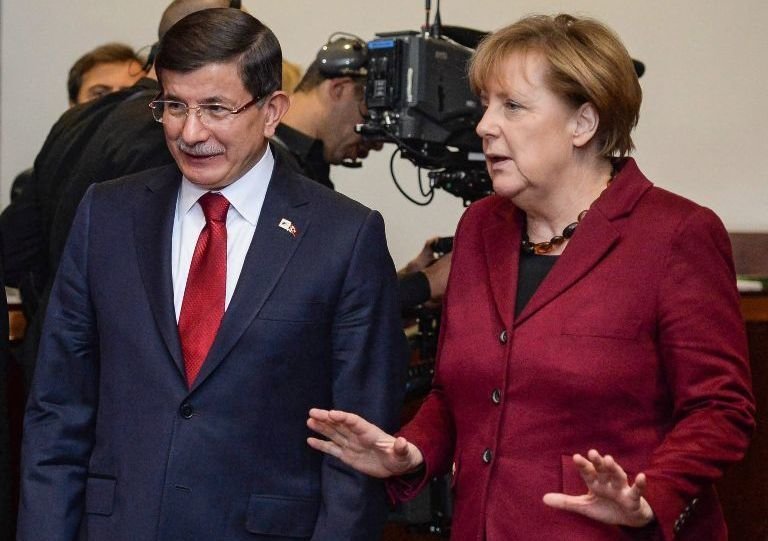 El primer ministro turco, Ahmet Davutoglu, conversa con la canciller alemana, Angela Merkel.