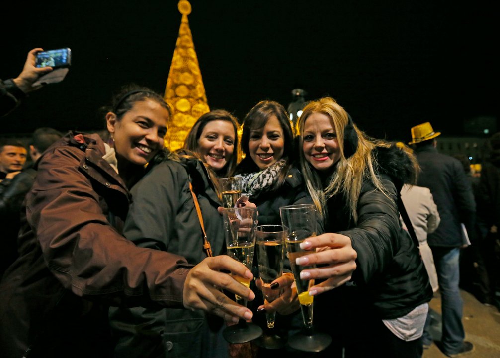 Cuatro jóvenes brindan por el año nuevo en la Puerta del Sol de Madrid.