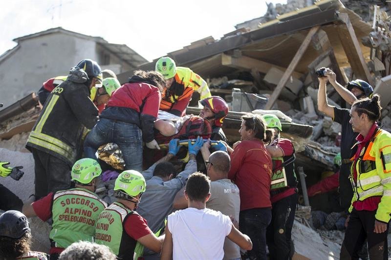 Un hombre herido (c) es rescatado por los equipos de emergencia de Amatrice