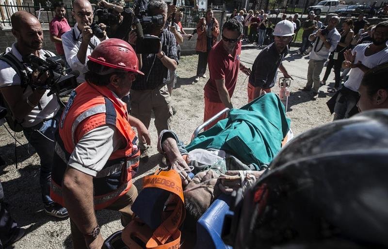 Miembros de los servicios de emergencia ayudan a uno de los supervivientes del terremoto
