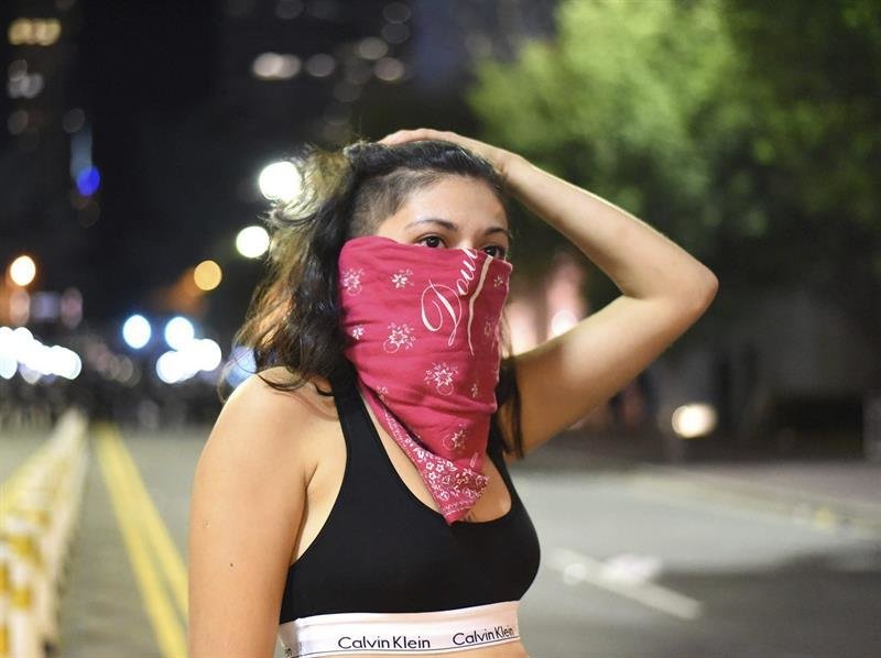 Una manifestante se cubre el rostro durante unos disturbios con la policía antidisturbios en Charlotte en Carolina
