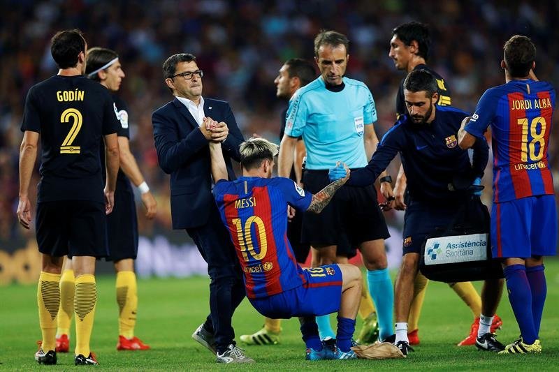 El delantero argentino del F. C. Barcelona, Leo Messi (c), es ayudado por los servicios médicos
