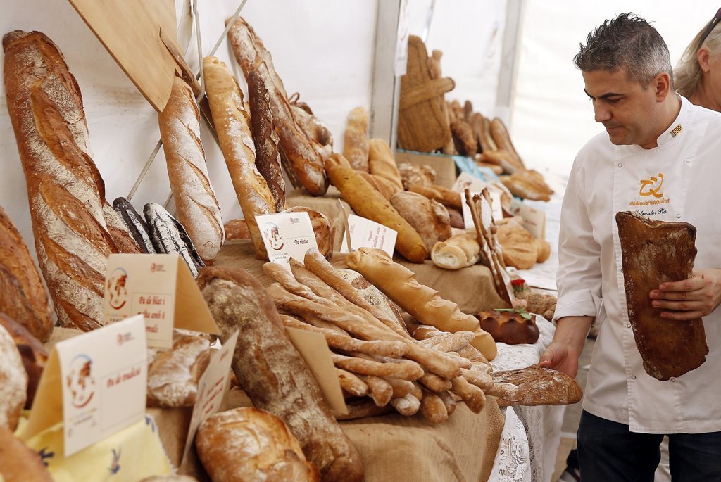 Un panadero ordena sus productos en un expositor valenciano con movito del Día de la Alimentación.