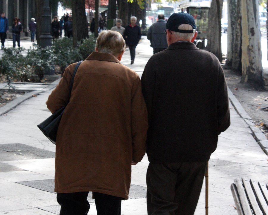 Dos personas mayores pasean por un parque en Valencia.