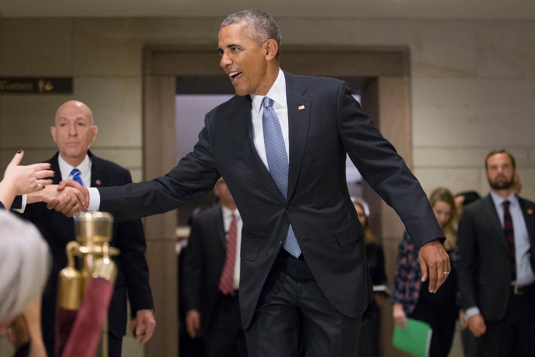 El presidente Barack Obama saluda a la salida de la reunión de los congresistas demócratas en el Capitolio.