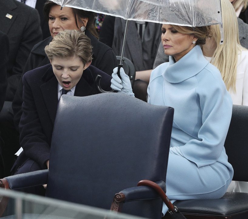 Melania Trump cubre de la lluvia a su hijo Barron, que bosteza, durante la investidura.