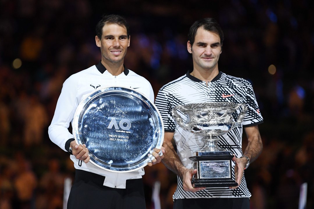 Rafa Nadal y Roger Federer, con los trofeos que conquistaron ayer en Melbourne Park.
