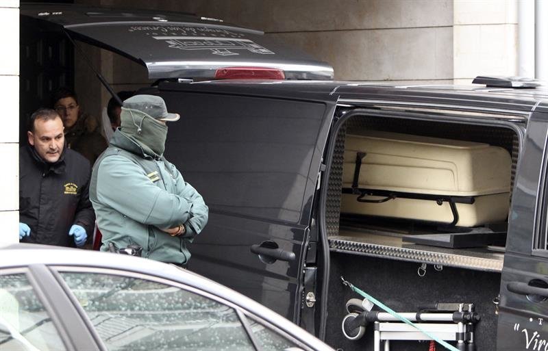 Un agente de la Guardia Civil permanece junto al furgón de los servicios funerarios