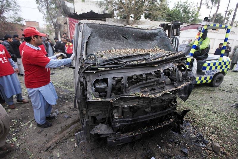 Miembros de los servicios de emergencia retiran un vehículo calcinado del lugar del atentado en Peshawar (Pakistán)