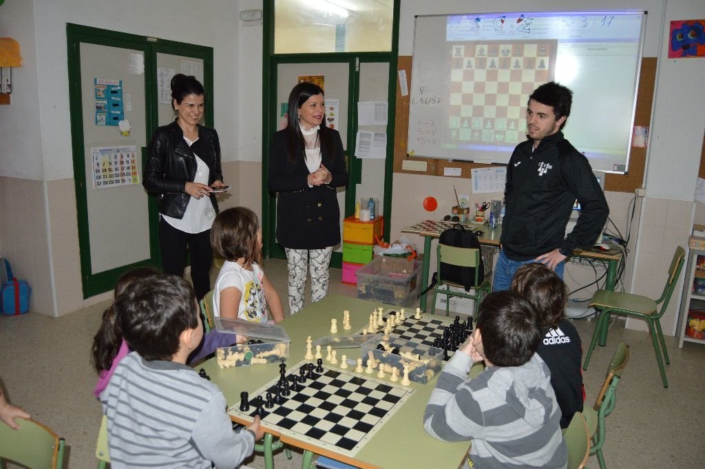 Nidia Arévalo y Kely Monzón, con escolares y el monitor de ajedrez,  en su visita al colegio de Petelos.