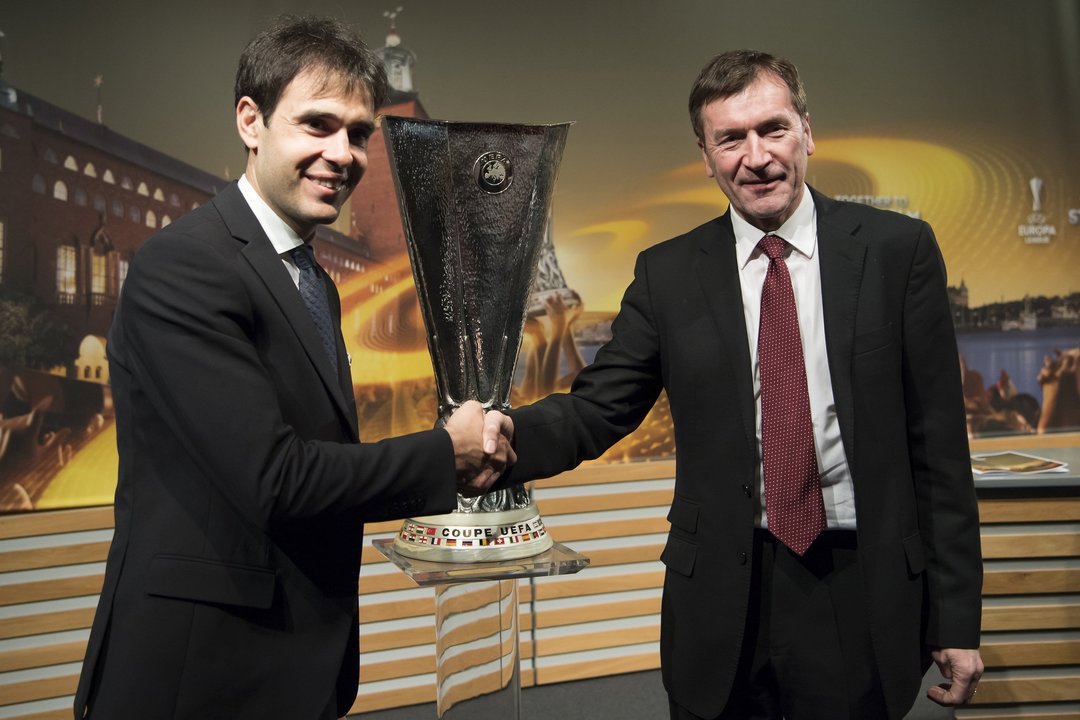 Borja Oubiña, representante del Celta ayer en el sorteo de Nyon, saluda al secretario del United, John Alexander, ante el trofeo de la Liga Europa.