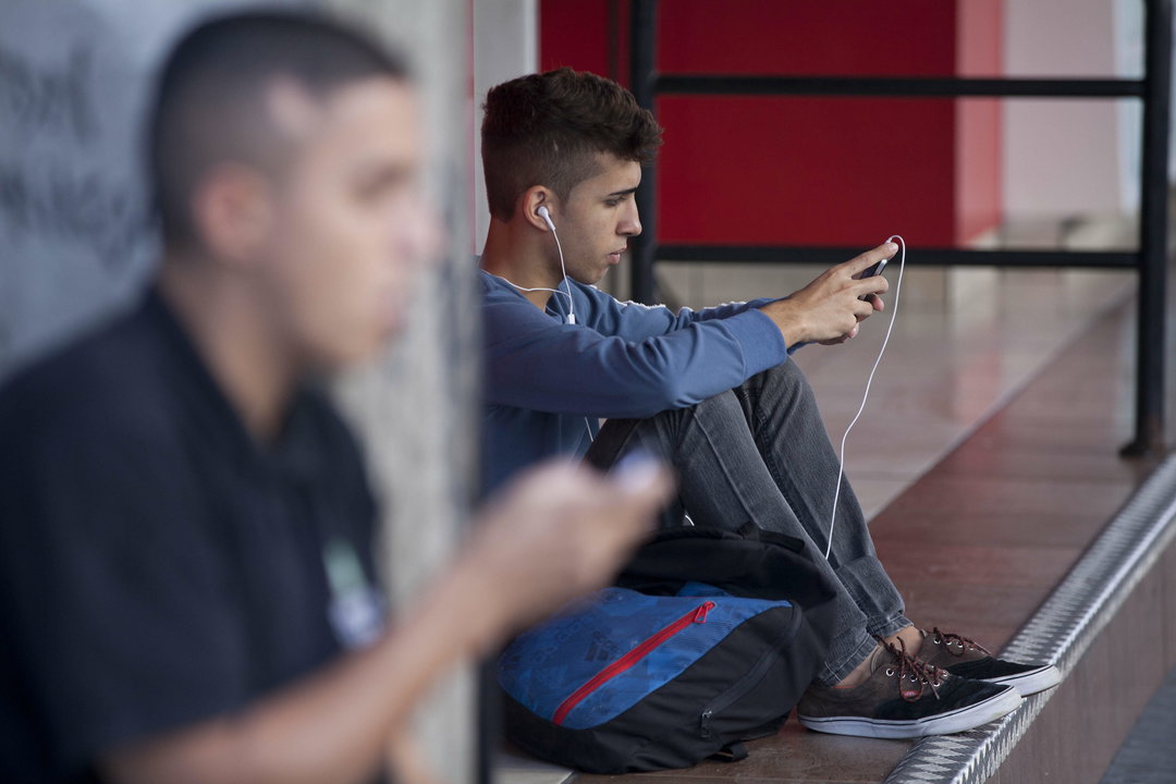 Dos jóvenes consultan sus teléfonos móviles.