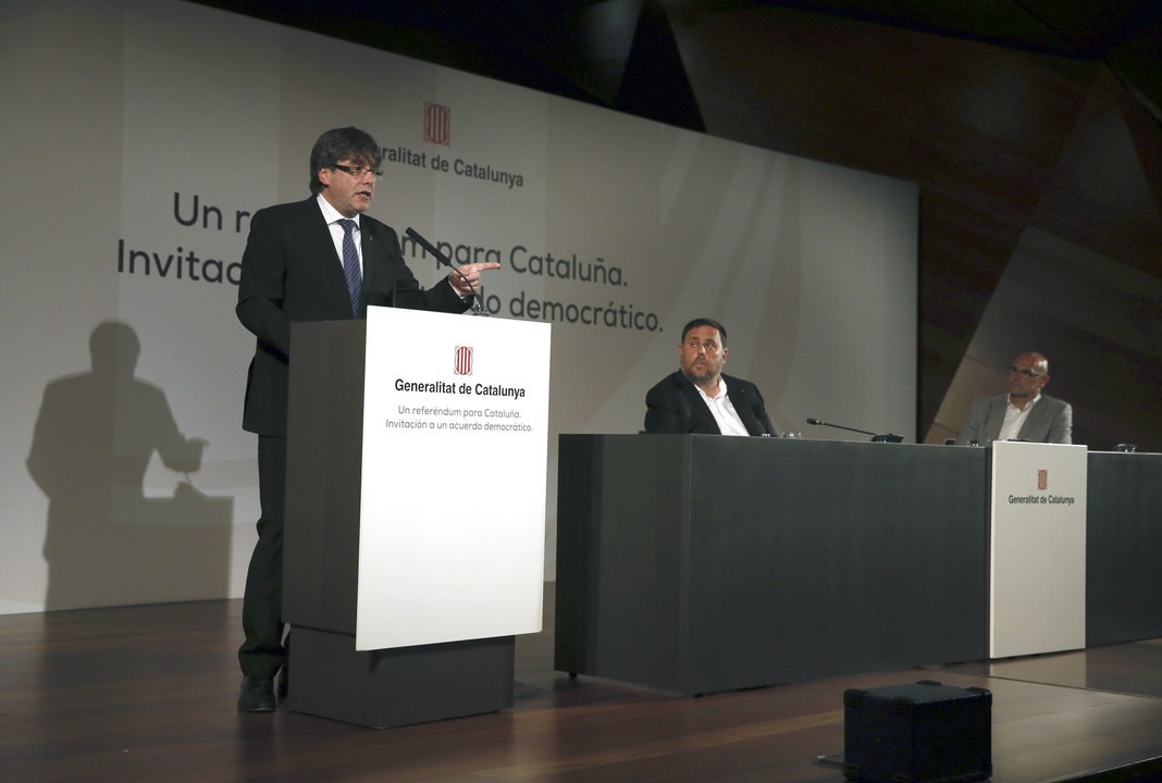 Carles Puigdemont, durante su intervención, ante la mirada de Oriol Junqueras y Raúl Romeva.