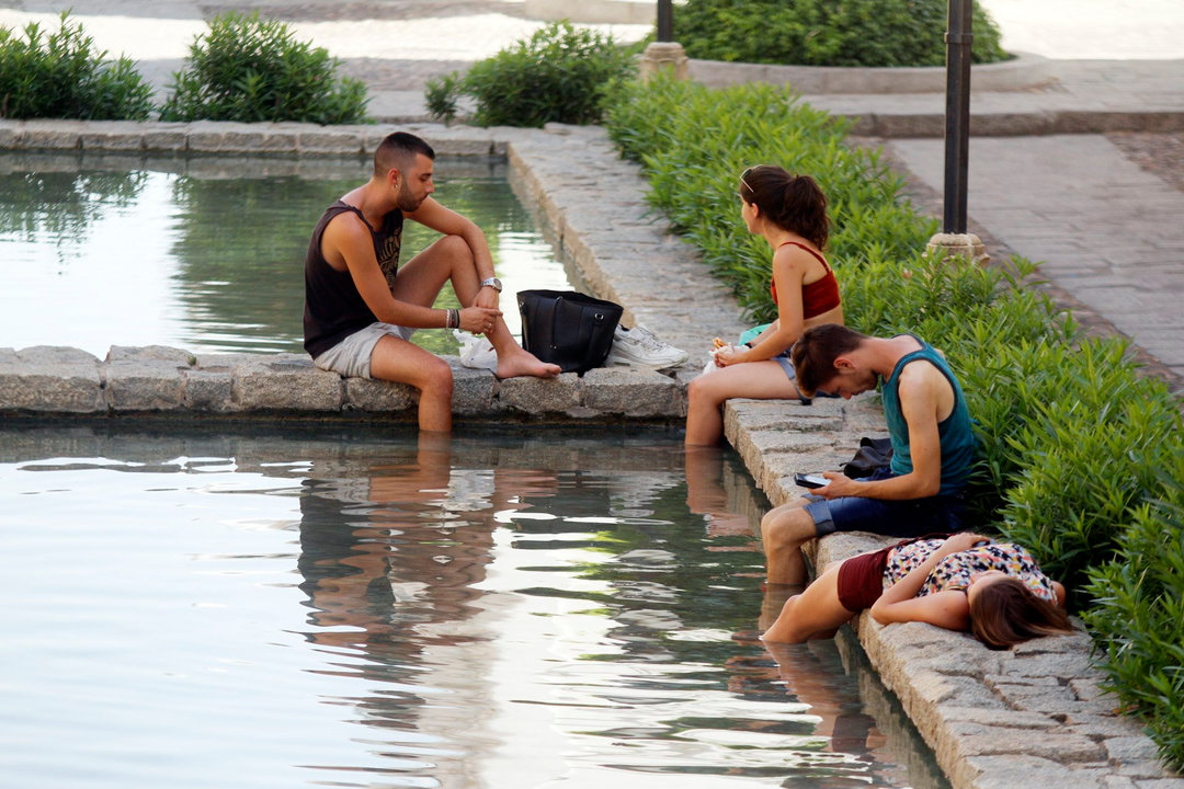 Unos jóvenes se refrescan en una de las fuentes del centro de Córdoba para mitigar el calor.