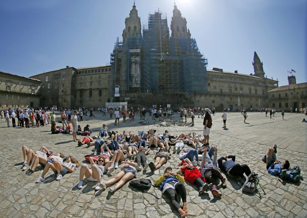 Varios grupos de peregrinos descansa completamente agotados ante la Catedral de Santiago.