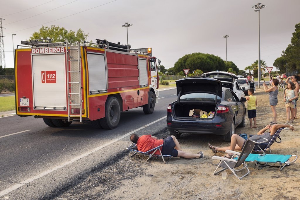 Viajeros atrapados en la zona de Matalascañas observan el paso de un camión de bomberos.