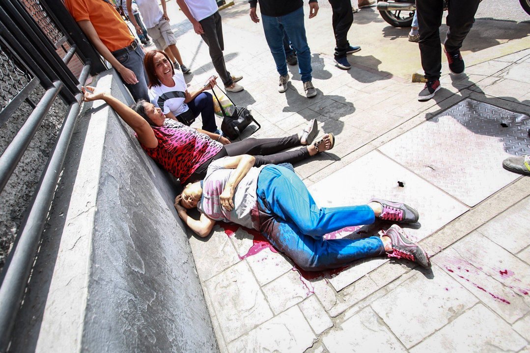 Dos mujeres yacen en el suelo víctimas de los disparos de los militares adeptos al oficialismo.