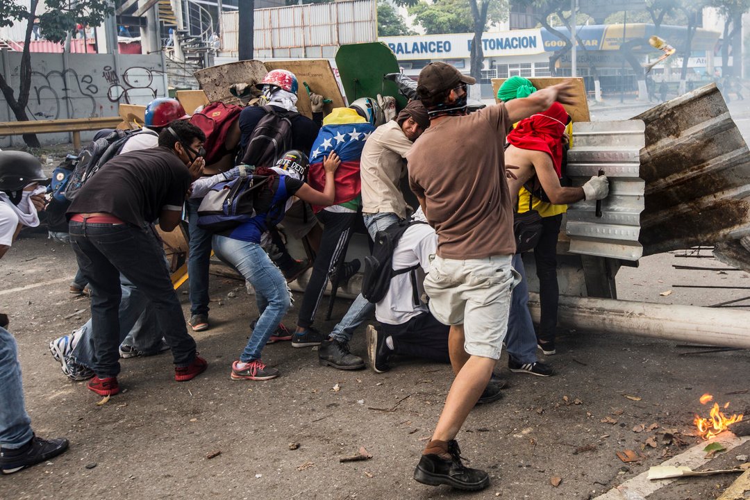 Un grupo de opositores se parapeta tras una barricada en una calle de Caracas.