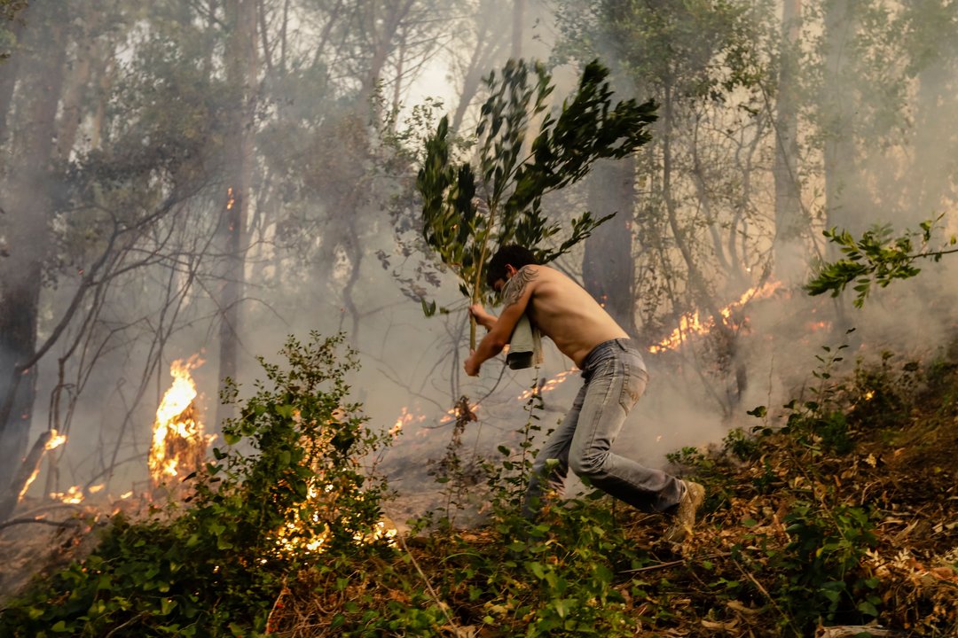 Un vecino lucha contra las llamas en un incendio en el distrito de Coímbra.