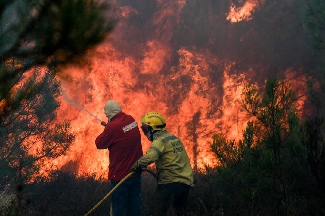 Dos bomberos intentan controlar un incendio, en las cercanías de Maçao, en el centro de Portugal.